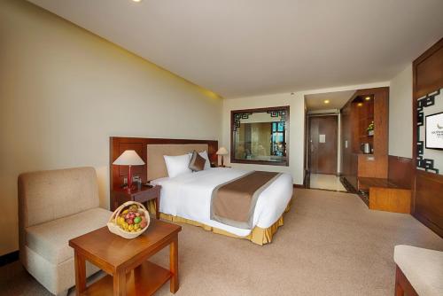 a hotel room with a bed and a chair at Muong Thanh Holiday Hoi An Hotel in Hoi An