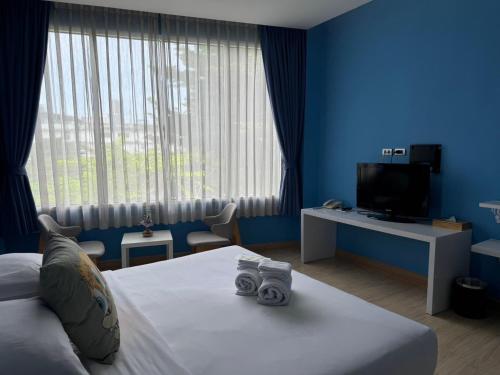 a blue room with a bed and a television at Beat Hotel Bangkok in Bangkok