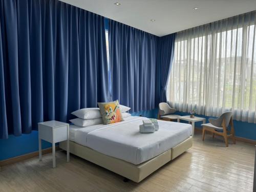 a bedroom with a large bed and blue curtains at Beat Hotel Bangkok in Bangkok