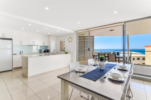 a kitchen and dining room with a table and chairs at Redvue Holiday Apartments in Redcliffe