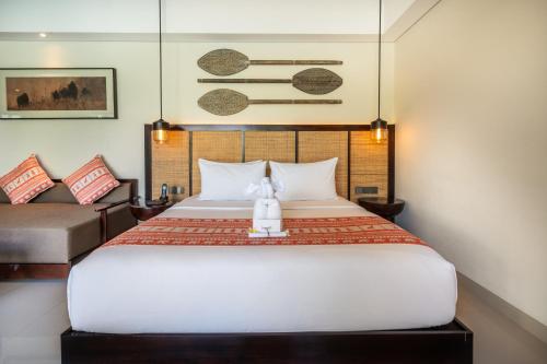 a bedroom with a large white bed and a couch at Sanctoo Suites & Villas in Gianyar