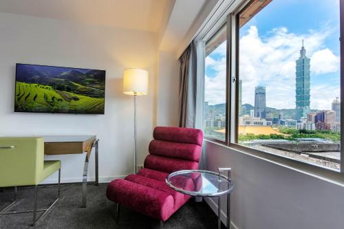 a room with a chair and a desk and a window at United Hotel in Taipei