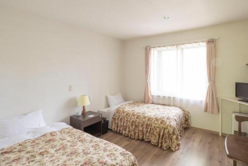 a hotel room with two beds and a window at カナリアンホテル in Tateshina