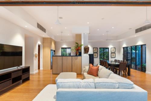 a living room with a white couch and a dining room at 35 Beachfront Mirage Port Douglas in Port Douglas