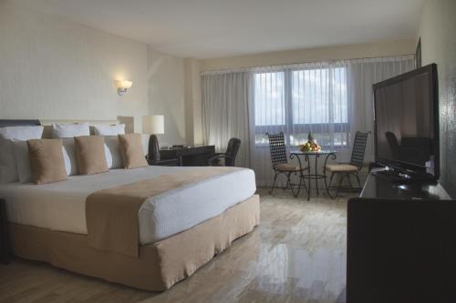 um quarto de hotel com uma cama grande e uma televisão em Smart Cancun the Urban Oasis em Cancún