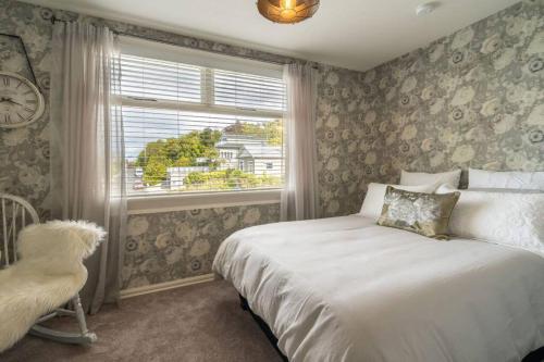 una camera con letto, finestra e orologio di Sea Salt Apartment Dunedin 3 Bedrooms & Sea Views a Dunedin