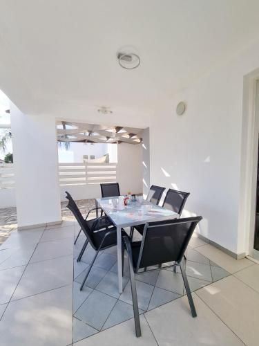 a dining room with a glass table and black chairs at Beach Villa With Private Pool And BBQ 17 in Pervolia