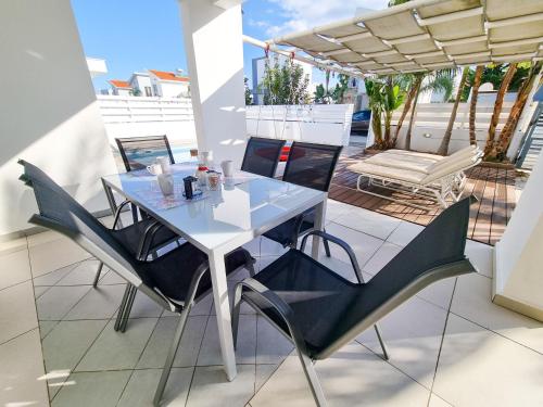 a white table and chairs on a balcony with a patio at Beach Villa With Private Pool And BBQ 17 in Pervolia