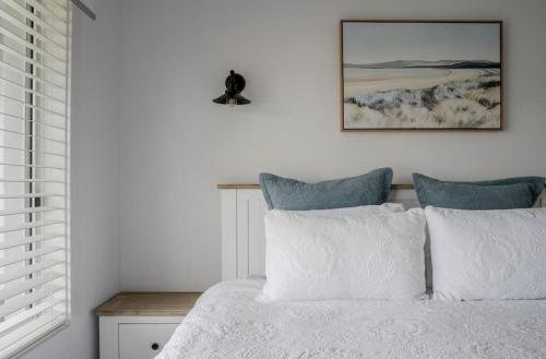 a bedroom with a bed with white sheets and blue pillows at Water's Edge in Culburra Beach