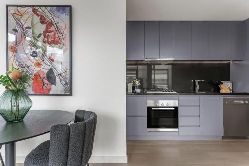 a kitchen with a table with chairs and a painting at King Street Apartments by Urban Rest in Sydney