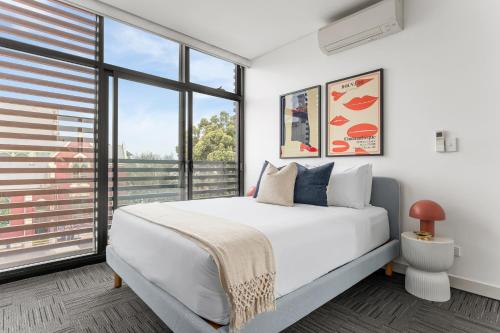 a bedroom with a white bed and large windows at King Street Apartments by Urban Rest in Sydney