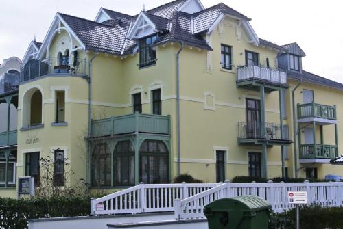 a large yellow house with a white fence in front of it at Villa Laura 12 in Kühlungsborn