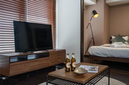 sala de estar con TV de pantalla plana y cama en Fancy2, en Sapporo