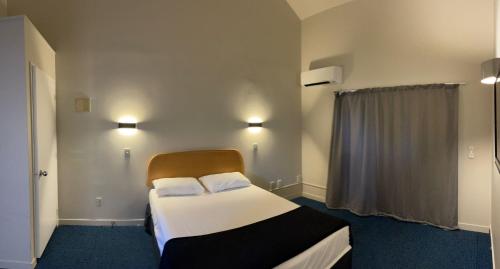a bedroom with a bed with white sheets and pillows at Rayland Epsom Motel in Auckland