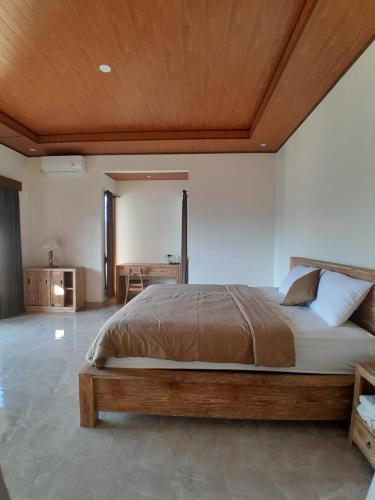 a bedroom with a large bed with a wooden ceiling at Ubud nadi villa in Tegalalang