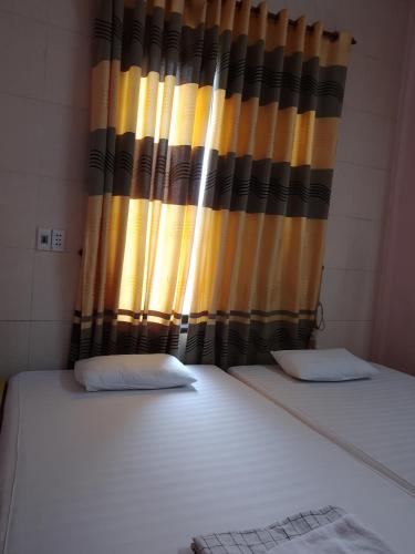 a bedroom with two beds and a curtain at Nhà nghỉ Hằng Nga in Dong Hoi