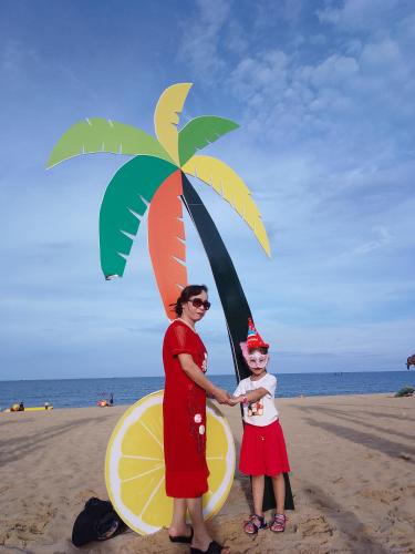 a woman and a child on the beach with a palm tree at Nhà nghỉ Hằng Nga in Dong Hoi