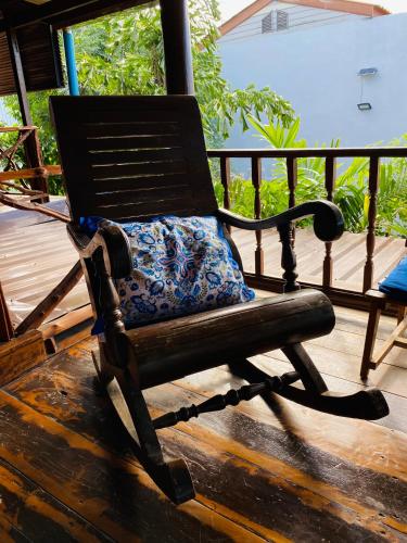 a wooden rocking chair sitting on a deck at Banthai Guesthouse in Phetchaburi