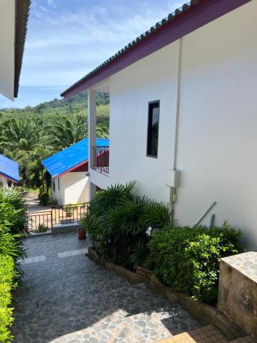 a white house with a balcony and a patio at Sawasdee Home Stay Resort & Pool in Khao Lak