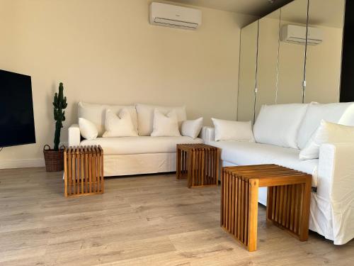 ein Wohnzimmer mit einem weißen Sofa und Holztischen in der Unterkunft SZAFIROWE APARTAMENTY 4 z widokiem na morze RESORT HEVENIA in Pogorzelica
