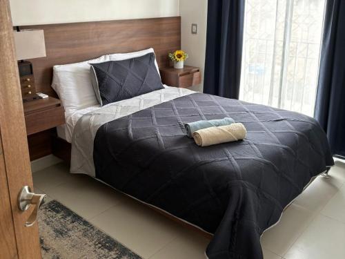 a bed with a black comforter and a pillow on it at Aztec Penthouse in Ensenada