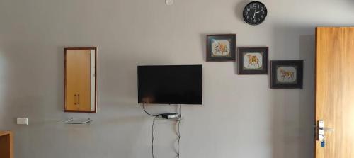 TīrthahalliにあるEden Garden - An Exquisite Home Stayの壁に絵画を飾った薄型テレビが備わります。