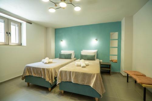 a bedroom with two beds and a blue wall at Renaissance Modern Stone House at Vryses - Private pool in Vryses