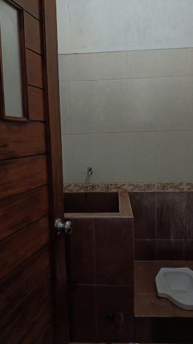 a bathroom with a tub and a toilet and a door at cokro homestay malioboro in Ngabean
