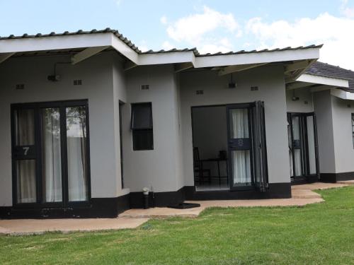 a house with glass doors and a green lawn at Tambarara Manor & Conference Centre in Harare