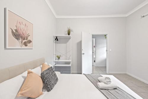 a white bedroom with a large white bed with pillows at Rustic Queen Room - Conveniently Located - Shared Bathroom in Sydney