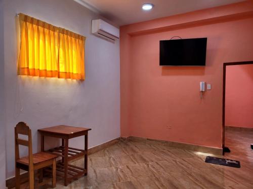 Una habitación con una mesa y un televisor en una pared. en Amazonas' House, en Iquitos