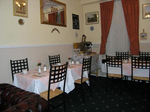 una sala da pranzo con tavoli e sedie e una cucina di Springfield B&B a Belfast