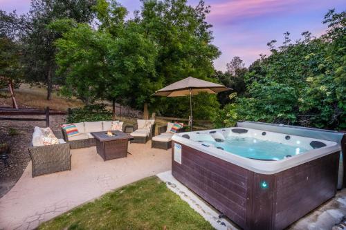 una bañera de hidromasaje en un patio con mesa y sillas en Emerald Escape! 50 Acres w/Hot Tub, Game Room, en Yosemite Forks