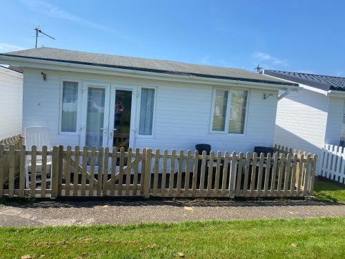 a white house with a wooden fence in front of it at Kebbles retreat in Mablethorpe