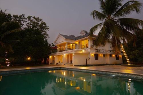 a house with a swimming pool in front of a house at Riveria Portico - River side 6 bedroom private pool Bungalow in Parūr