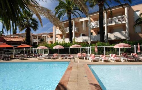un hôtel avec une piscine dotée de chaises et de parasols dans l'établissement Appartement accueillant à Golfe-Juan - 30 m² - Piscine, au Golfe-Juan