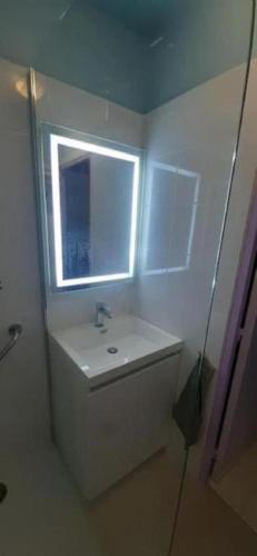une salle de bain blanche avec un lavabo et une fenêtre dans l'établissement Appartement accueillant à Golfe-Juan - 30 m² - Piscine, au Golfe-Juan