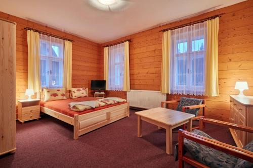 a bedroom with a bed and a table and windows at Penzion Flora in Janske Lazne