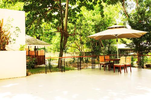 a patio with a table with an umbrella and chairs at Marianne Hotel in Puerto Princesa City