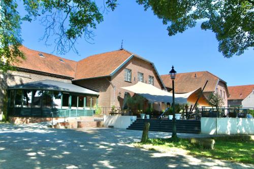 a large brick building with a table and chairs in front of it at Hotel Restaurant De Roosterhoeve in Roosteren