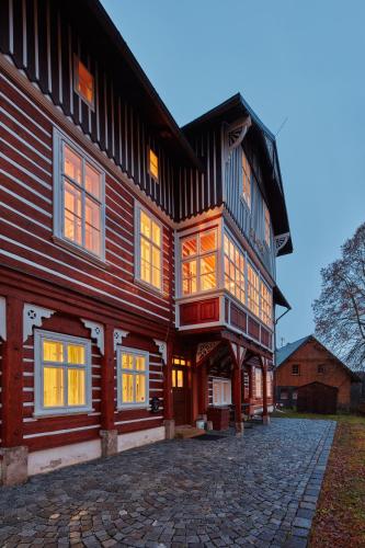 a large wooden house on a cobblestone street at Penzion Flora in Janske Lazne