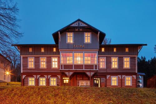 a large wooden house with many windows on a hill at Penzion Flora in Janske Lazne