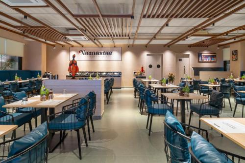 a dining room with tables and blue chairs at Stae Hotel-Madhapur in Hyderabad