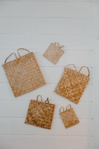 four wicker bags hanging on a white wall at La villa du jardin in Saint-Denis
