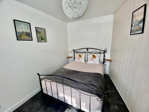 - une chambre blanche avec un lit noir dans l'établissement Le Nid du Sancy - 5P - Proche station de ski, à Le Mont-Dore