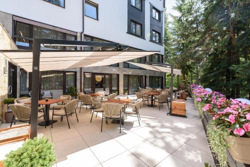 an outdoor patio with tables and chairs and flowers at Lion Hotel Borovets in Borovets