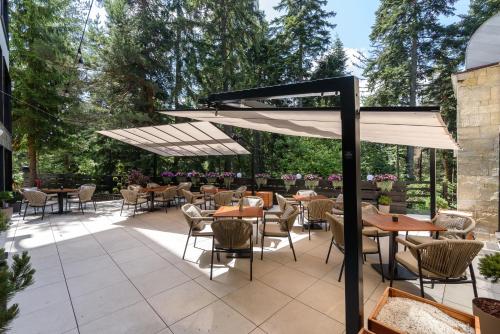 a patio with tables and chairs and an umbrella at Lion Hotel Borovets in Borovets