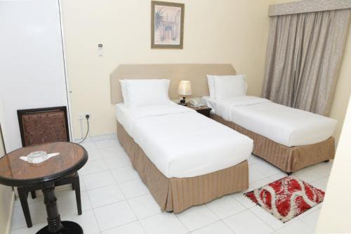 a hotel room with two beds and a table at Blue Sky Way Hotel in Dubai