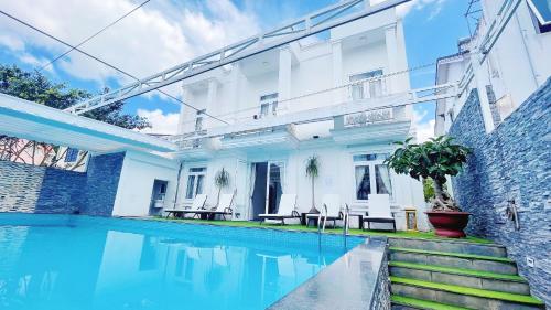 a swimming pool in front of a white house at Villa Camellia in Da Lat