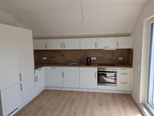 a kitchen with white cabinets and a sink at Sunny Side Apartments in Postmünster